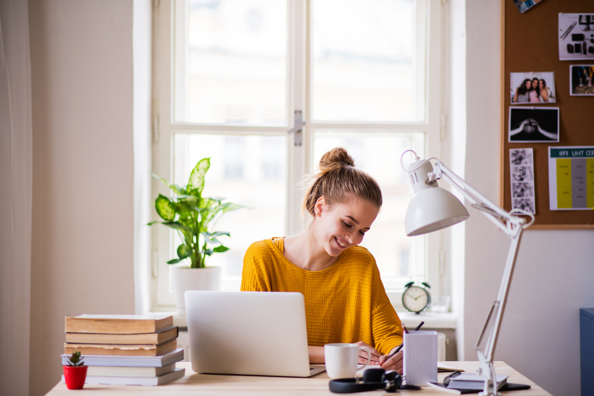 Chica en su escritorio sonriendo ante su portátil mientras escribe.